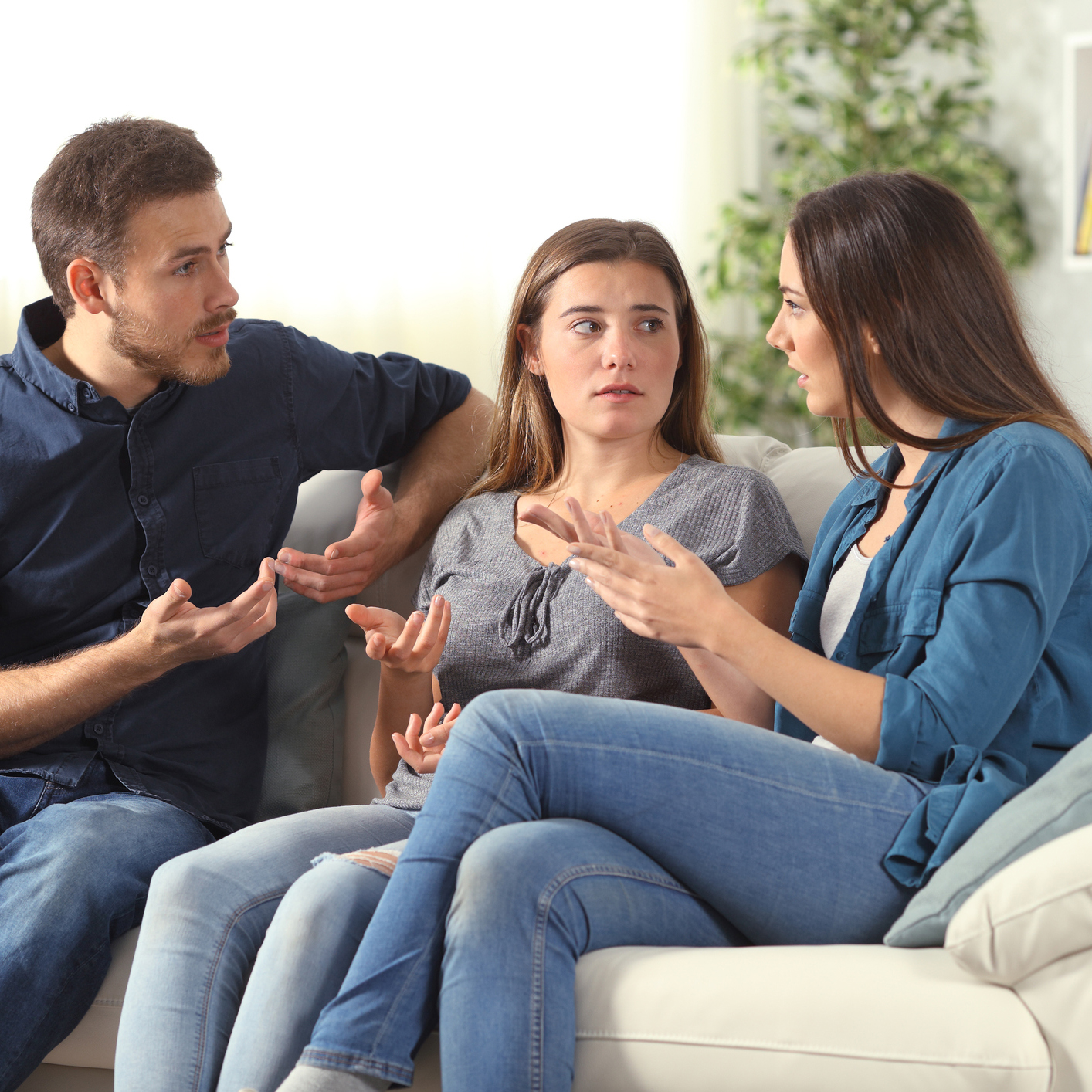 Three serious friends talking sitting on a couch at home