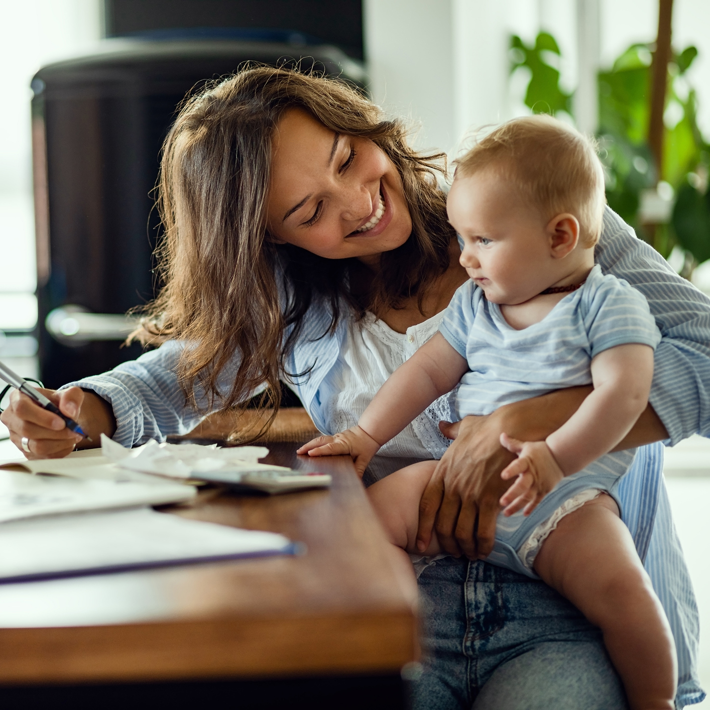 Happy mother talking to her baby while working at home.