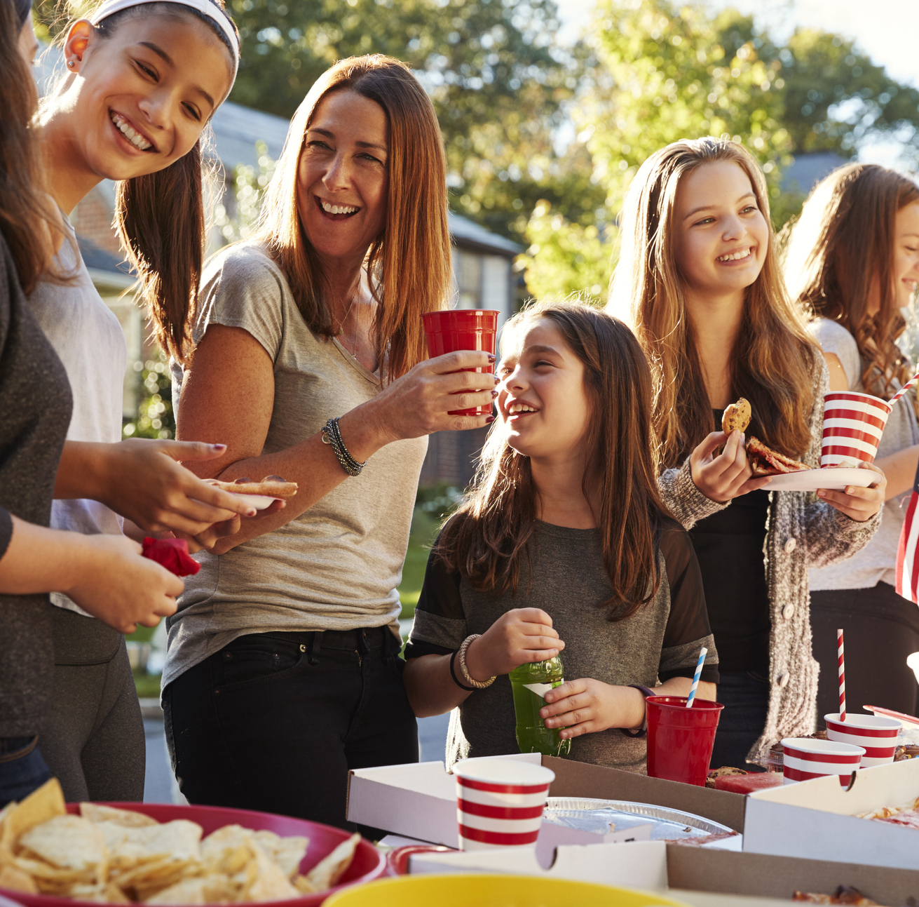 Girls stand talking at a block party food table, close up