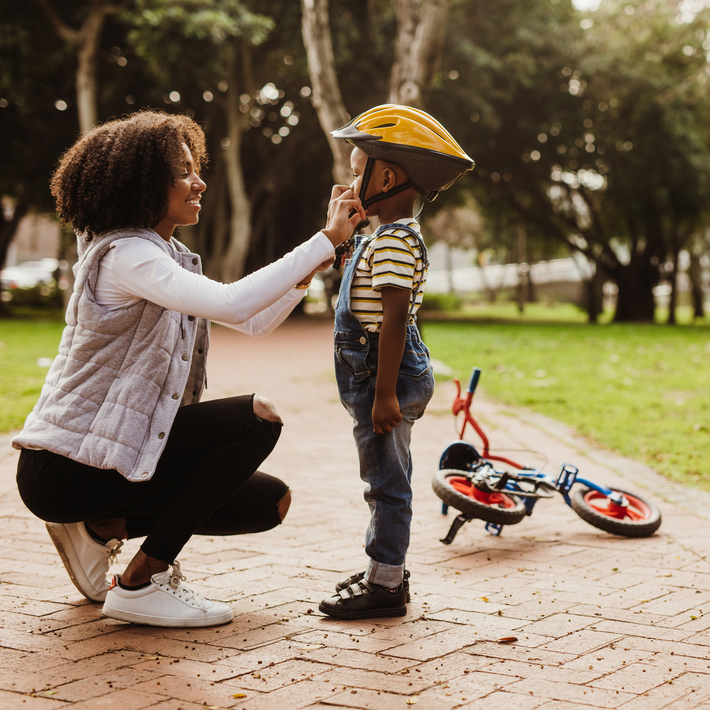 Mother helping son wearing helmet for cycling