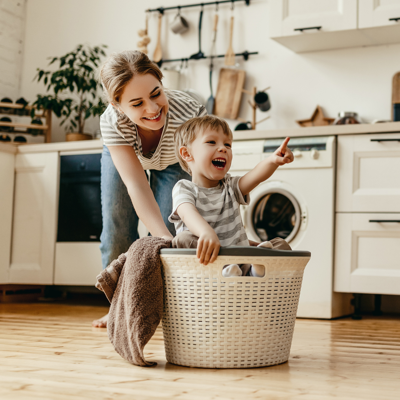 Happy family mother housewife and child in laundry with washing machine