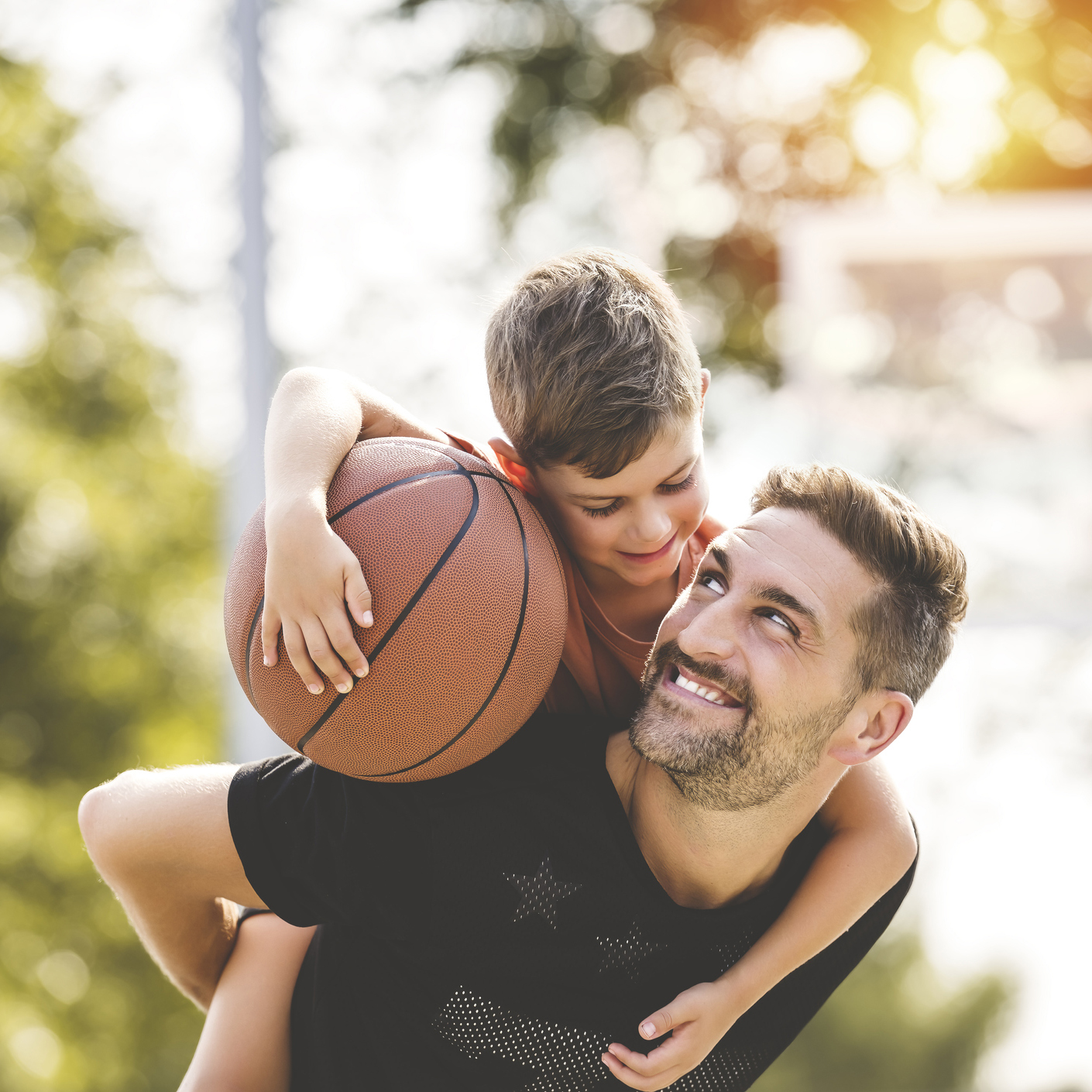 man and young boy playing basketball on a court, teaching little player and spending time outdoors