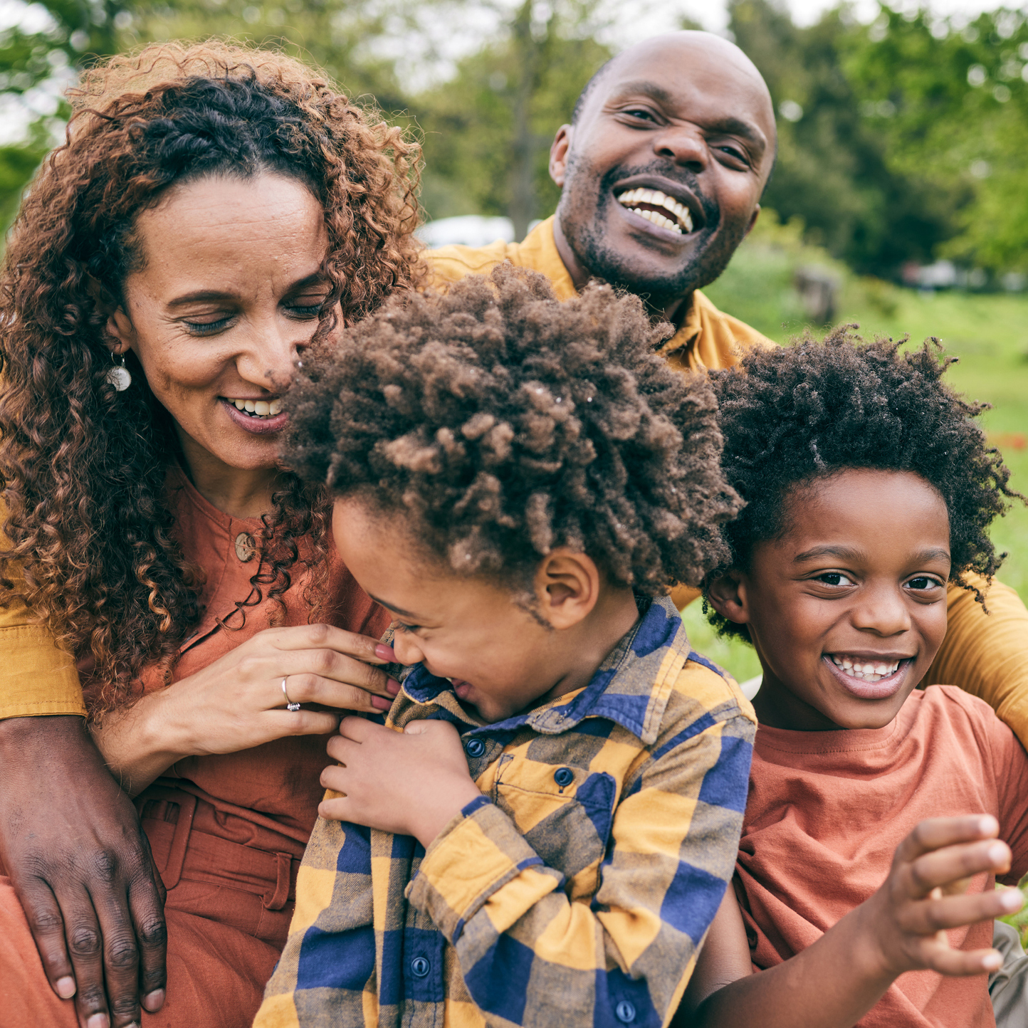 Happy black family, parents and children in a park in summer, smile and relax on grass field for love and fun in nature. Happiness, picnic and portrait of African people outdoor and playing together