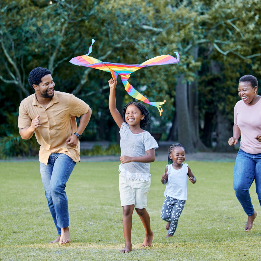Black family, kite and outdoor fun with parents and children having fun and playing outside at a park in nature. Energy, love and running while being active and bonding with man, woman and kids