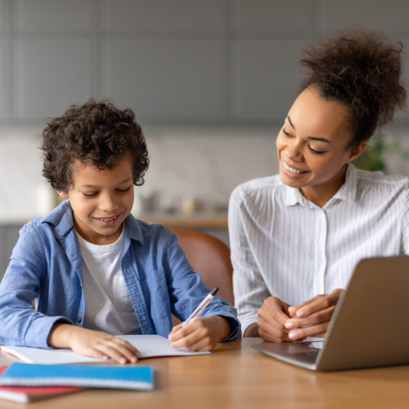 Black mother helps her son with homework at kitchen table