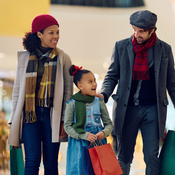 Happy black little girl and her parents buying in shopping mall during Christmas sales. Happy black little girl and her parents buying in shopping mall during Christmas sales.