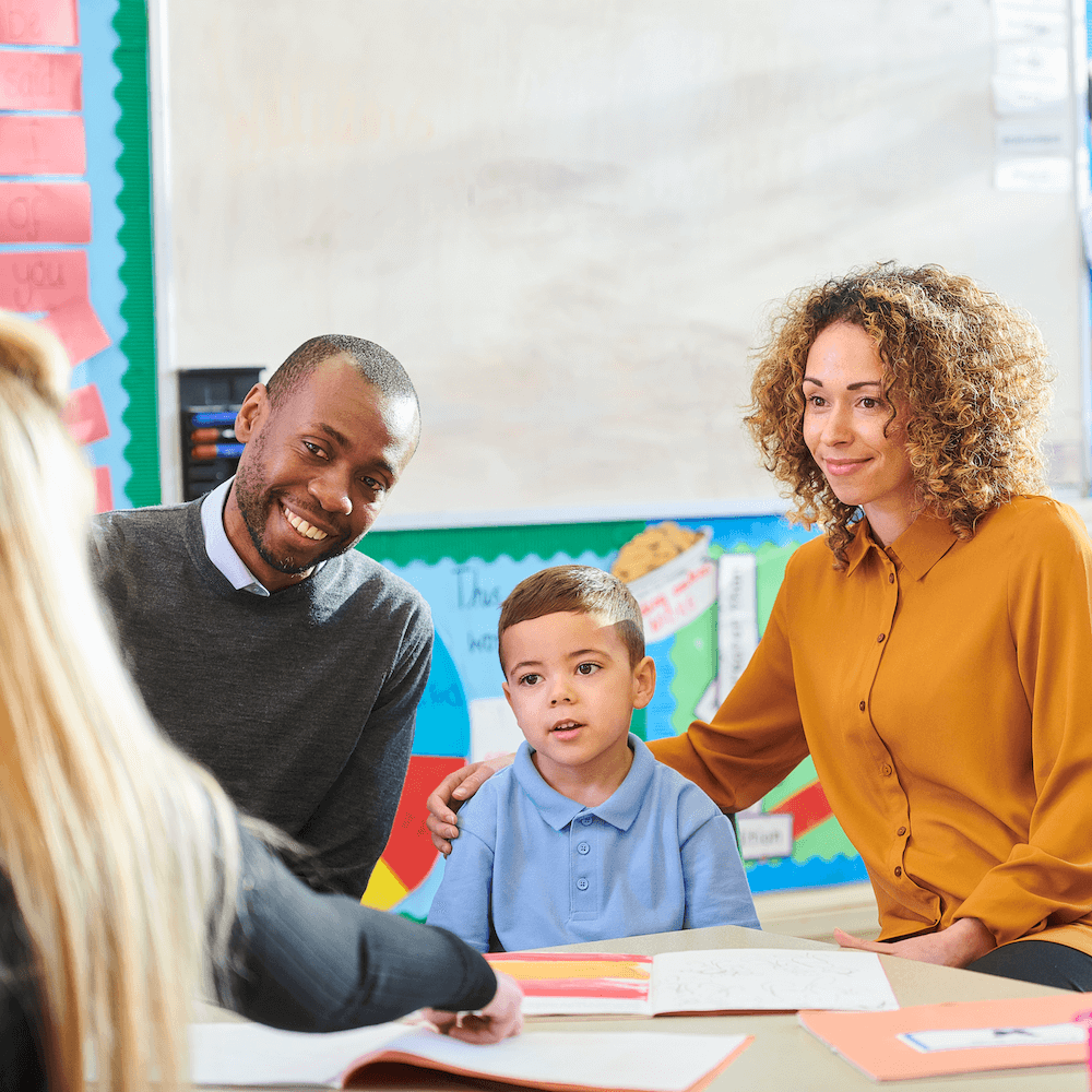 Parents with young child talking to his teacher in the classroom. Parents with young child talking to his teacher in the classroom.