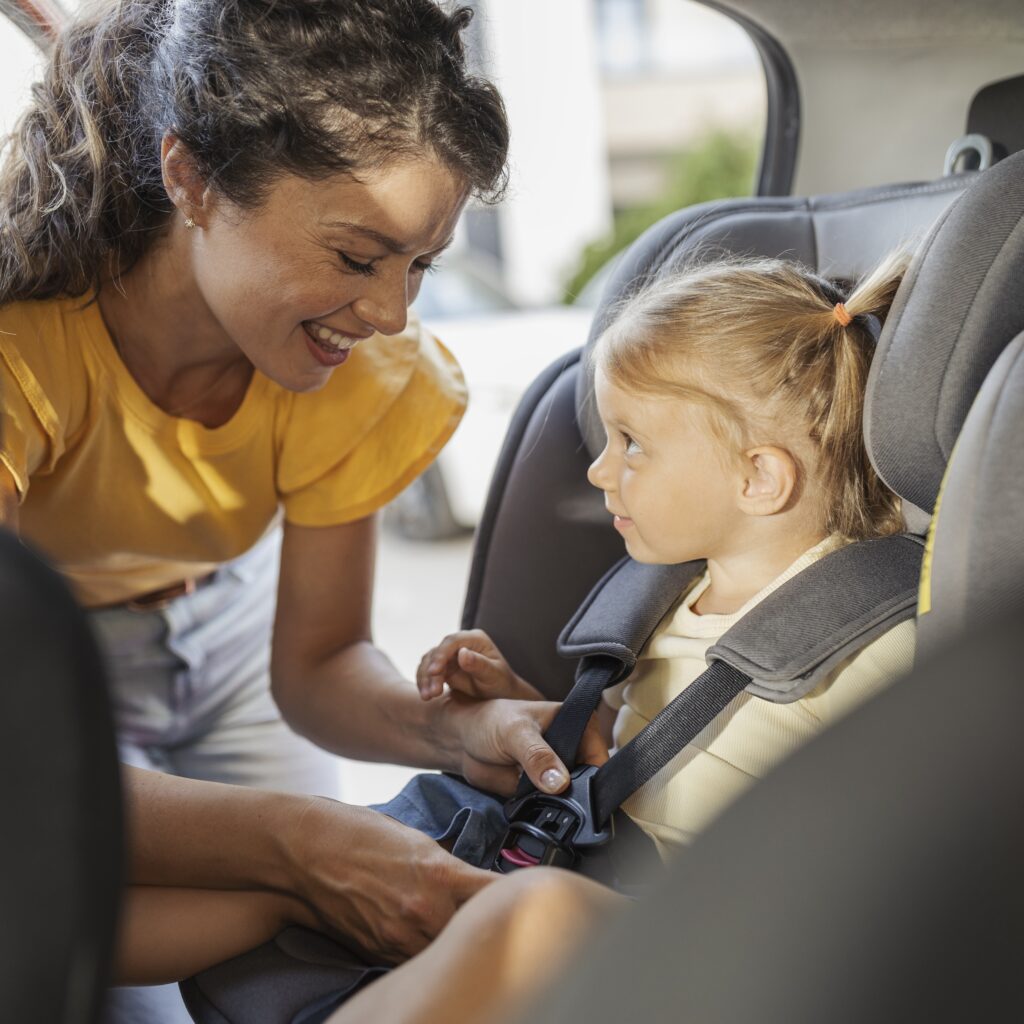 Mother helps daughter into car seat